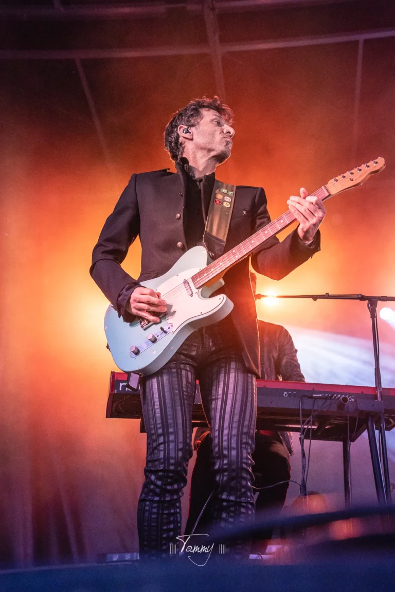 Guitariste de Rewind en solo sur scène, lumière orange et ambiance live pop rock à Angers